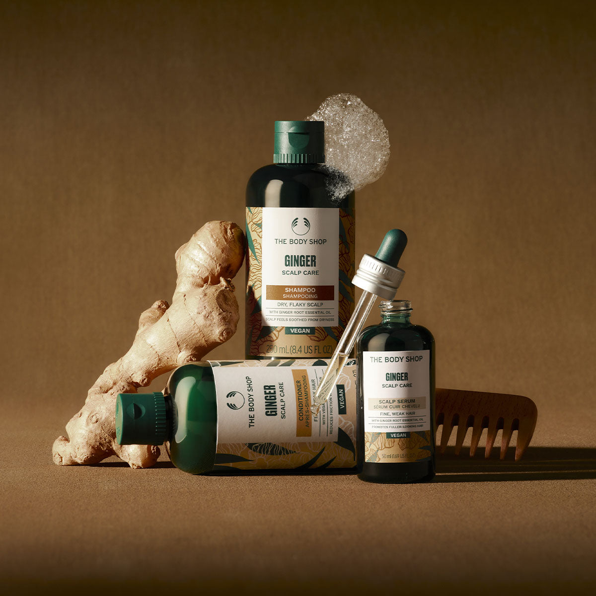The Body Shop Ginger Scalp Care products including shampoo, conditioner, and oil on a brown background