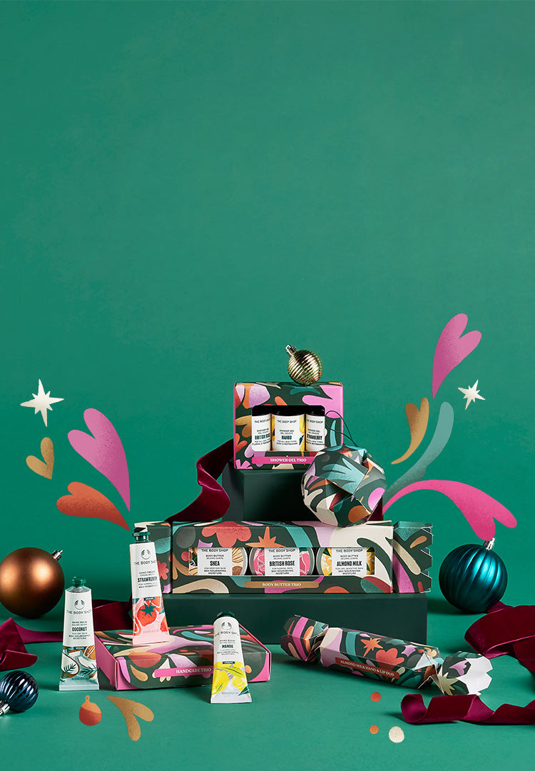 the body shop gift sets with Christmas ordainments on a vibrant green background