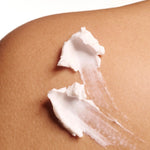 White cream being applied to a person's skin on a white background