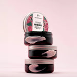 Stack of The Body Shop British Rose body butters on a pink background