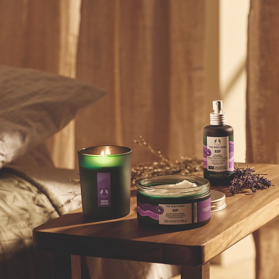 Aromatherapy products including a candle, jar, and bottle on a wooden surface with a warm background.