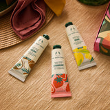 Three hand cream tubes from The Body Shop on a wooden surface