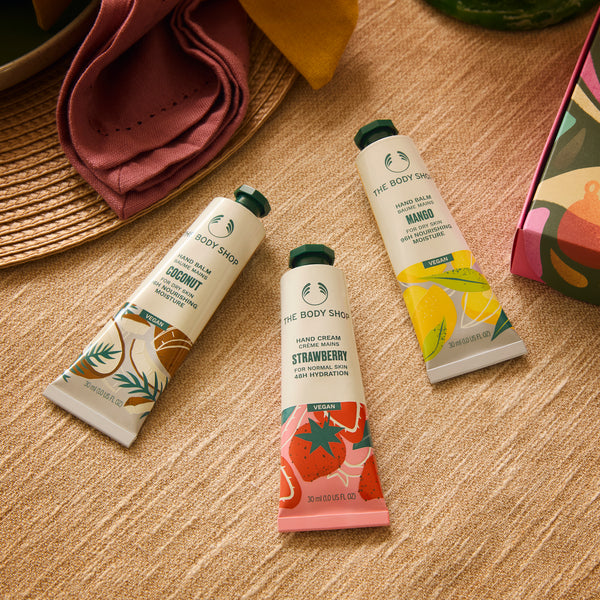 Three hand cream tubes from The Body Shop on a wooden surface