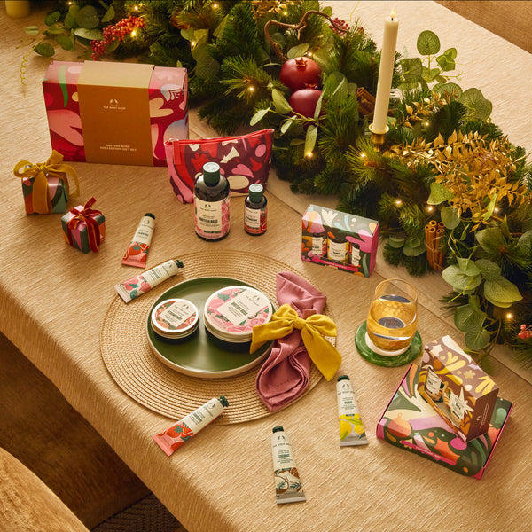 Table setting with beauty products, a candle, and decorative items on a tablecloth.