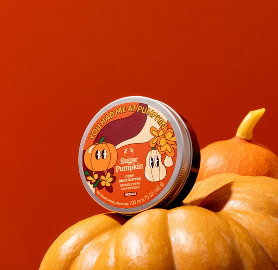 Container of 'Sugar Pumpkin' on a pile of pumpkins with a red background
