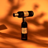 Two wine bottles stacked on top of each other with an orange background