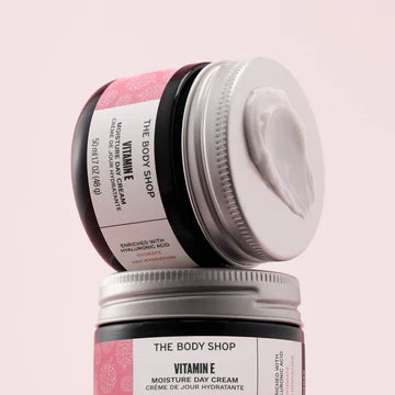 Two jars of The Body Shop Vitamin E Moisturizing Cream on a pink background