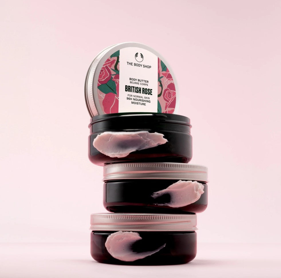 Stack of The Body Shop British Rose body butters on a pink background