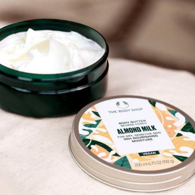 The Body Shop Almond Milk body butter with packaging on a neutral background