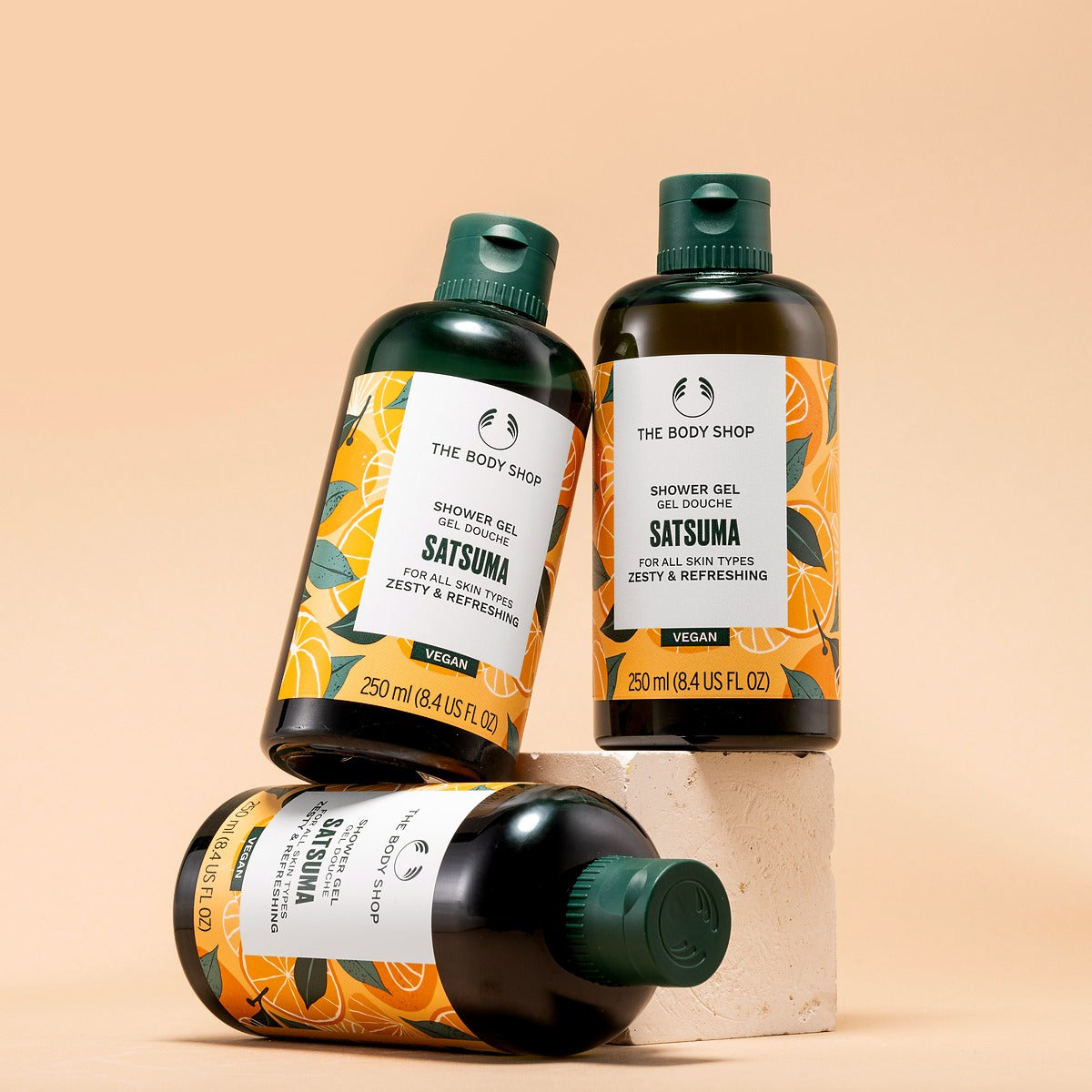 Three bottles of The Body Shop Satsuma shower gel on a beige background