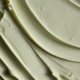 A close-up texture shot of a thick, creamy off-white cosmetic cream with smooth, swirled ridges.