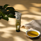 Tube of body wash with a bowl of liquid on a textured surface with leaves in the background