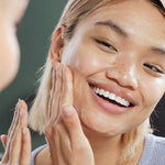 Woman applying a skincare product to her face with a blurred background
