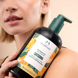 Person holding a bottle of The Body Shop Satsuma shower gel with a beige background