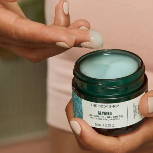Person holding a jar of The Body Shop Seaweed product with a blurred background