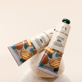 Two tubes of The Body Shop hand balm on a textured surface with a neutral background