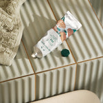 Hand cream tube on a tiled bathroom floor with a towel nearby