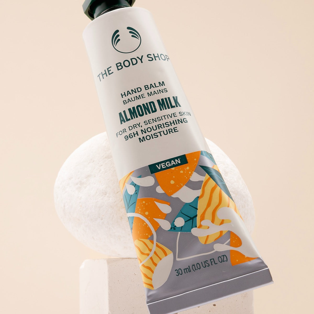 Hand balm tube with colorful design on a beige background