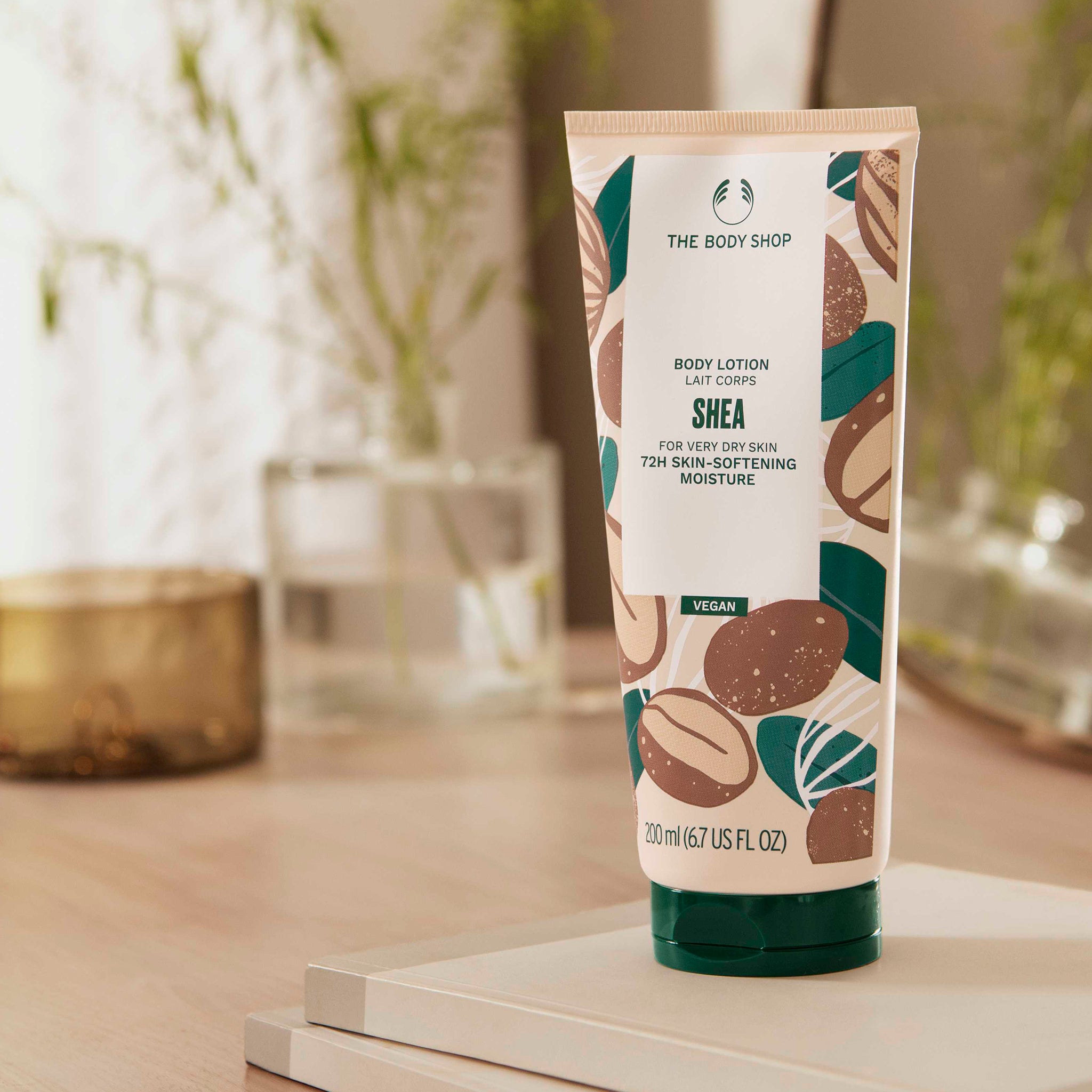 Shea body lotion tube from The Body Shop on a wooden surface with blurred background