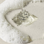 Clear liquid being poured onto a white surface with bubbles