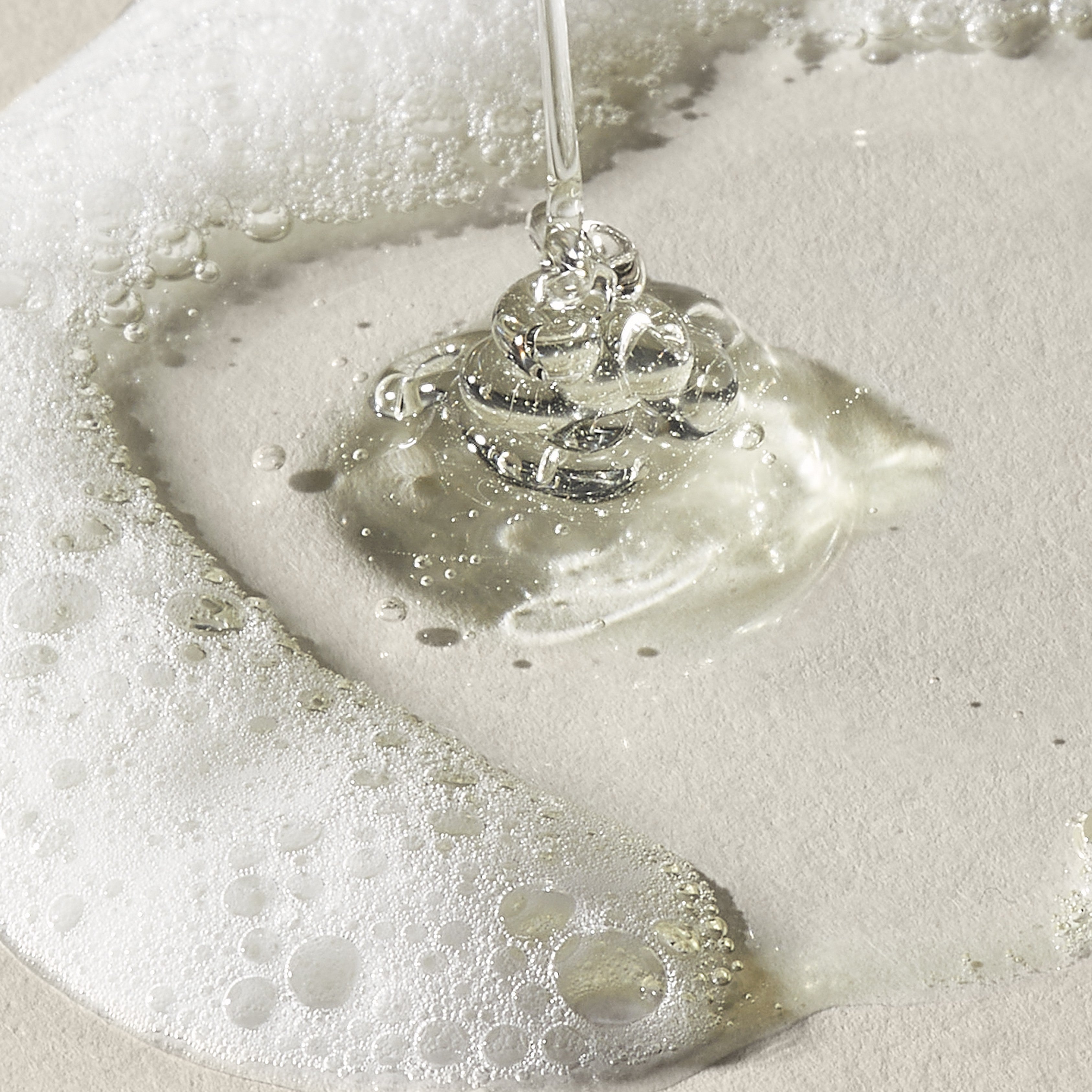 Clear liquid being poured onto a white surface with bubbles