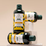 Three bottles of The Body Shop Banana Smoothie Shampoo on a beige background