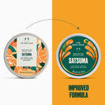 Two round tins of The Body Shop Satuma body butter are shown side by side on a split white and orange background, with a dotted arrow between them and the text 'IMPROVED FORMULA' below. The left tin has a white label with orange citrus illustrations, and the right tin has a dark green label with orange citrus illustrations.