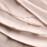 A close-up texture shot of a thick, creamy cosmetic cream with smooth, swirled layers in a warm off-white shade.