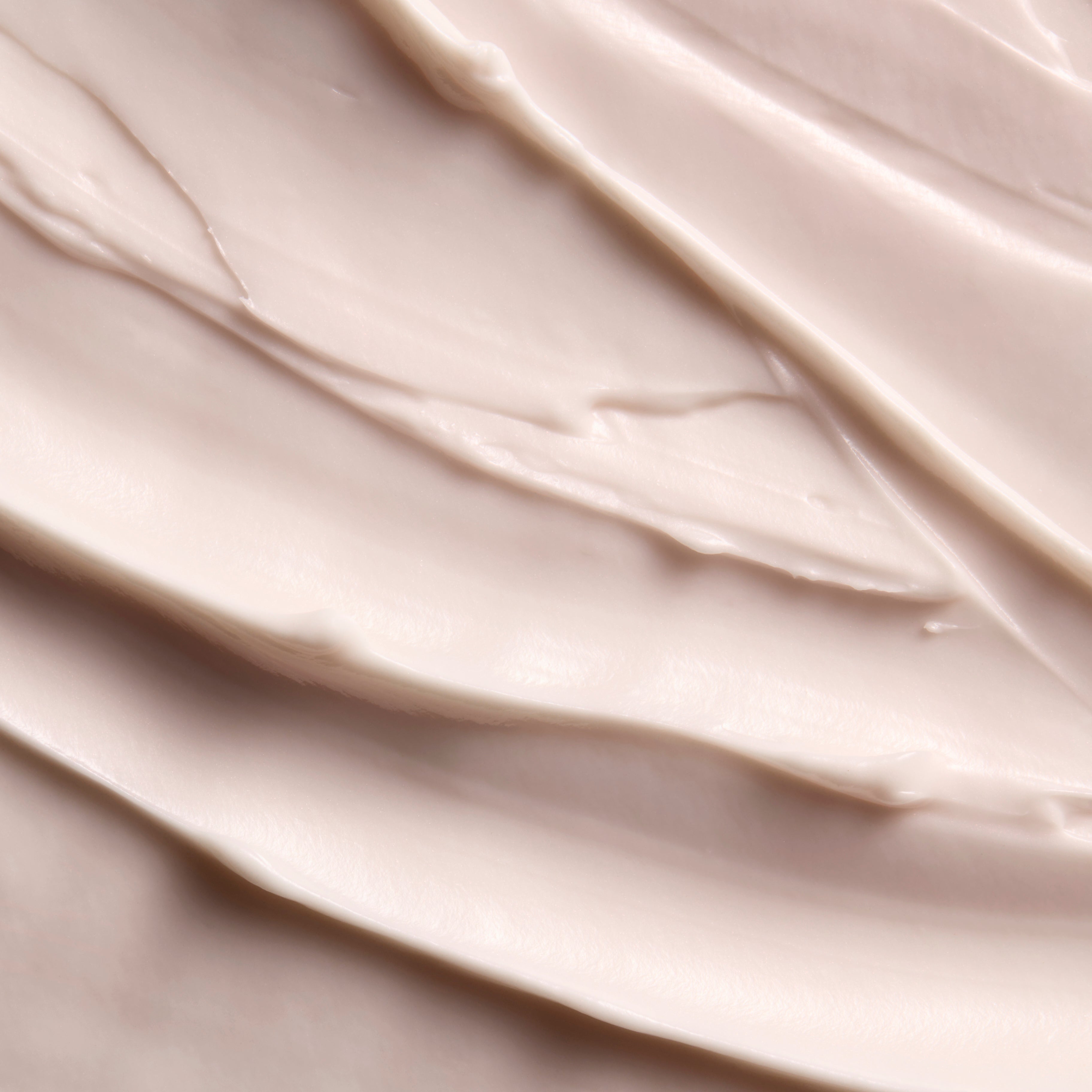 A close-up texture shot of a thick, creamy cosmetic cream with smooth, swirled layers in a warm off-white shade.