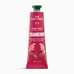 A squeeze tube of The Body Shop Hand Cream Creme Mains in Cranberry, featuring a deep pink-red tube with white text, a green cap, and illustrations of strawberries and hands at the bottom, set against a plain white background.
