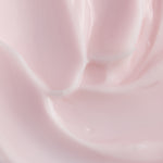 A close-up texture shot of a smooth, creamy pale pink cosmetic cream with soft swirls and a glossy finish.