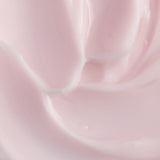 A close-up texture shot of a smooth, creamy pale pink cosmetic cream with soft swirls and a glossy finish.