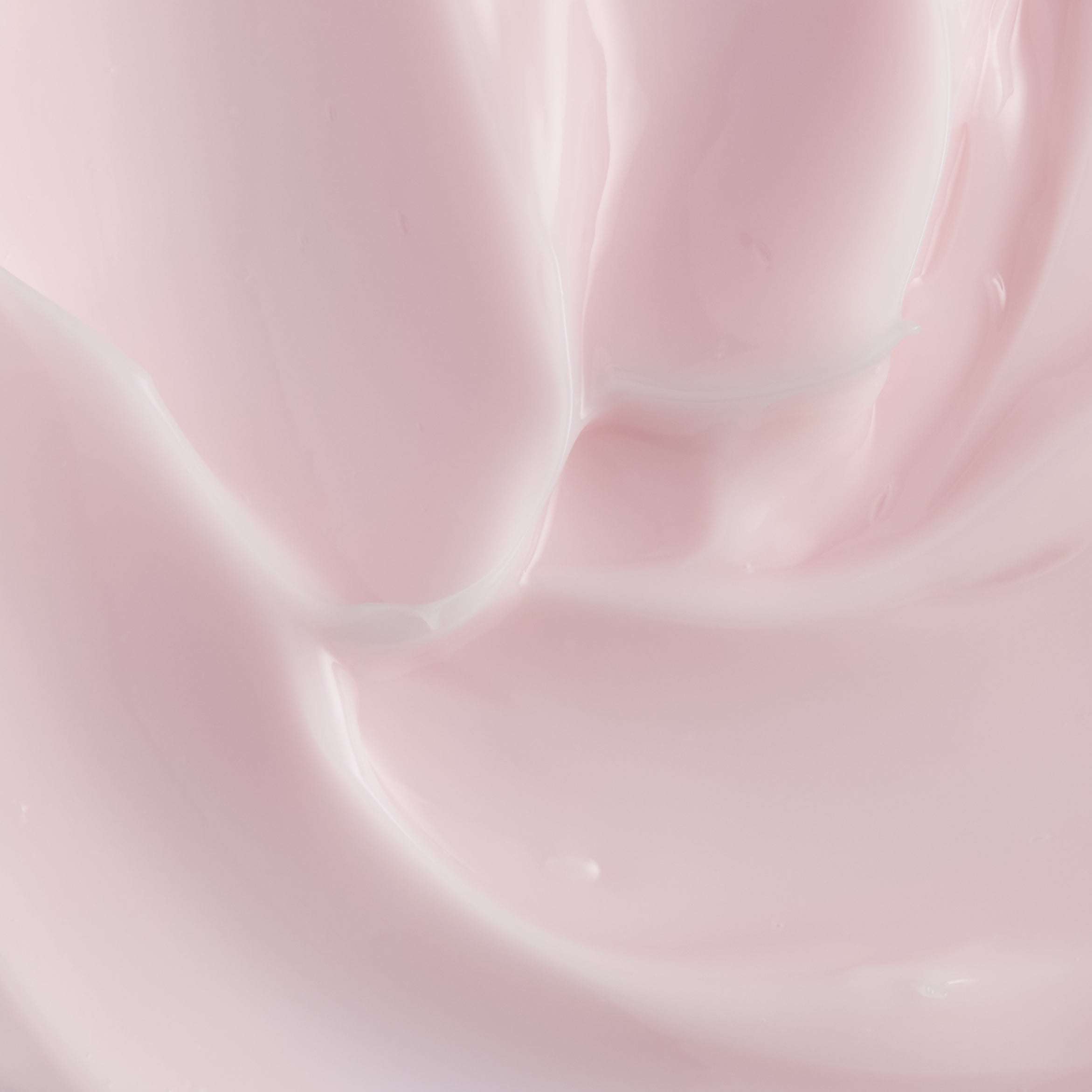 A close-up texture shot of a smooth, creamy pale pink cosmetic cream with soft swirls and a glossy finish.