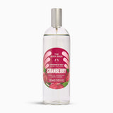 A 100ml bottle of The Body Shop Cranberry Fragrance Mist, featuring a clear bottle with a silver spray cap and a red and pink label with illustrations of cranberries, set against a plain white background.