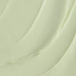 A close-up texture shot of a thick, creamy pale green cosmetic cream with smooth, flowing swirled lines.
