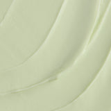 A close-up texture shot of a thick, creamy pale green cosmetic cream with smooth, flowing swirled lines.