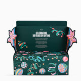 An open dark green gift box with decorative multicolor illustrations and the text 'CELEBRATING 50 YEARS OF GIFTING' on the inside lid, shown on a clean white background.