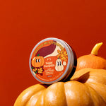 Container of 'Sugar Pumpkin' on a pile of pumpkins with a red background