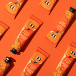 Pumpkin-themed hand cream packaging on an orange background