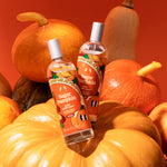 Two bottles of 'Sugar Pumpkin Body Mist' products surrounded by pumpkins on a red background