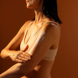 Woman with wet hair and arm lotion against a brown background