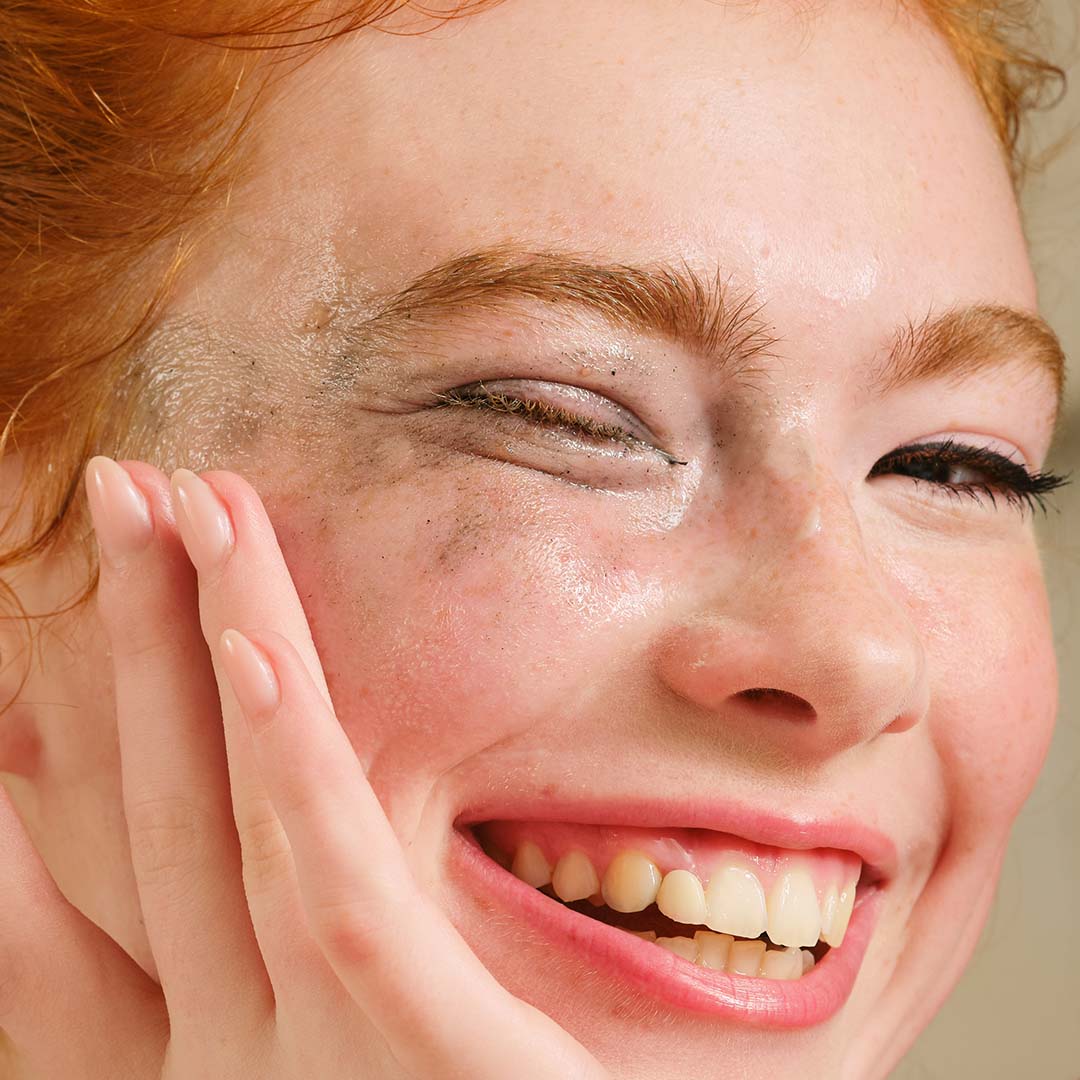 Close-up of a woman with freckles on her face, smiling.
