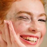 Close-up of a woman with freckles on her face, smiling.