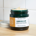 The Body Shop Almond Milk & Oat instant soothing mask jar on a wooden surface with a white background