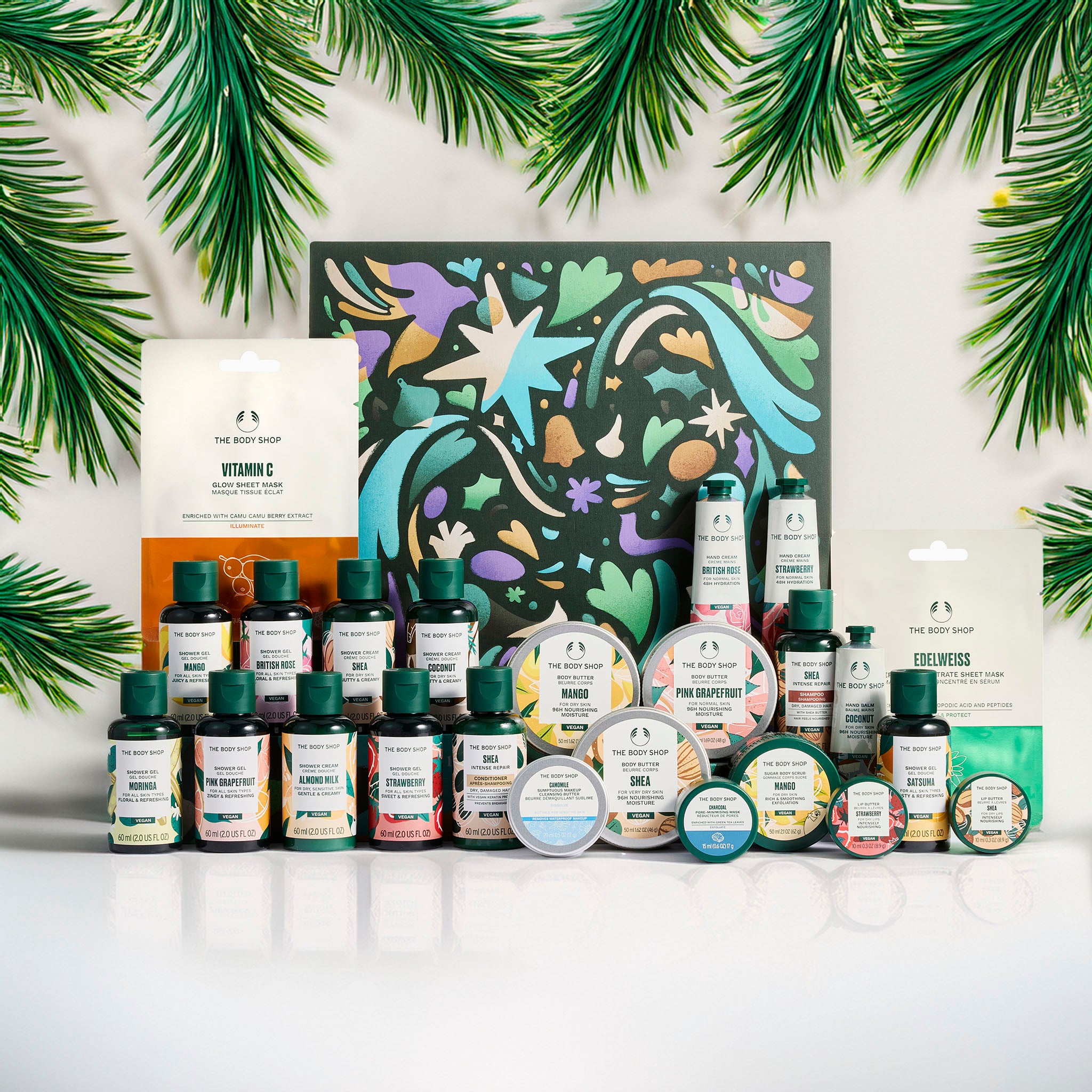 Collection of skincare products with decorative box and green leaves on a white background