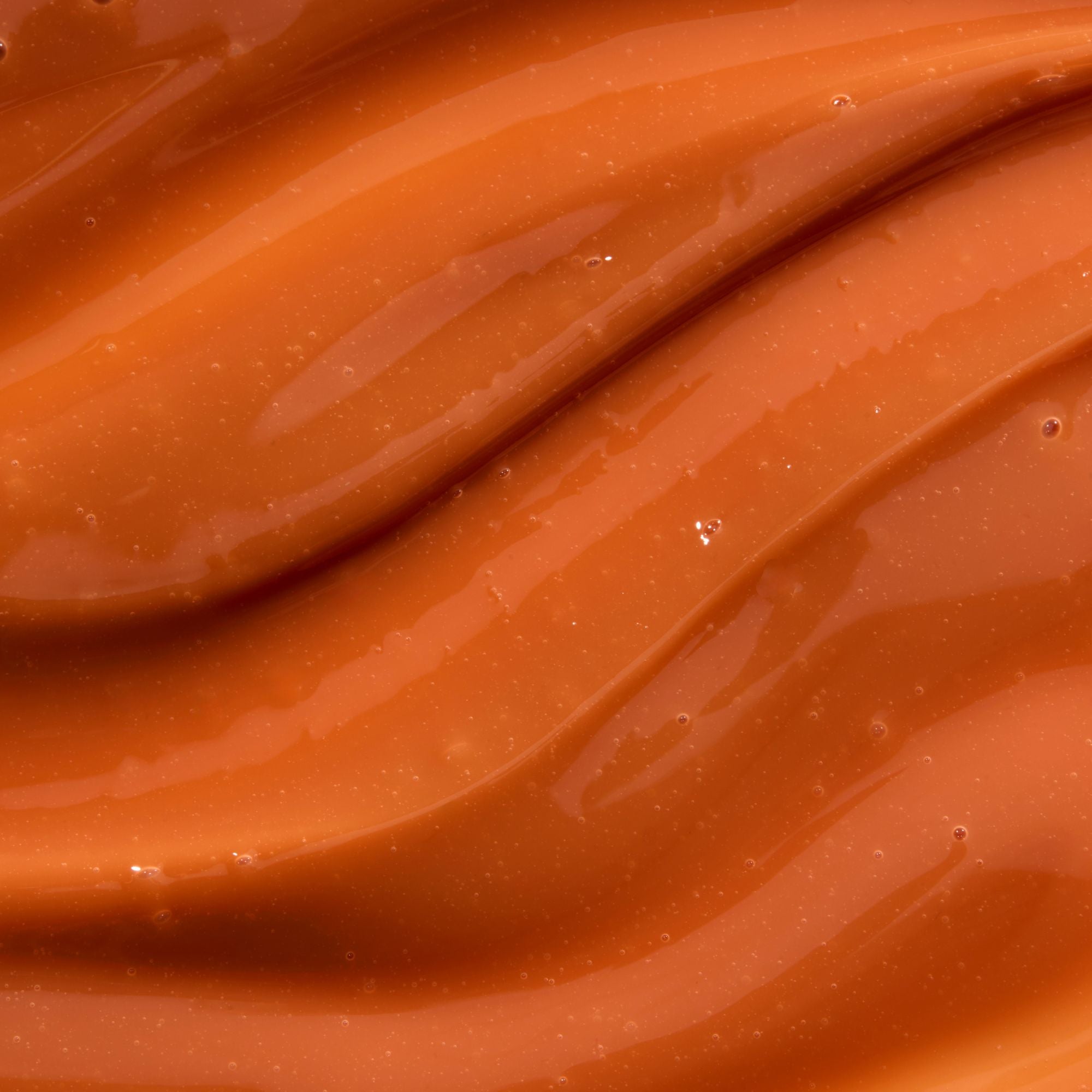 Close-up of smooth, glossy caramel colour lip balm