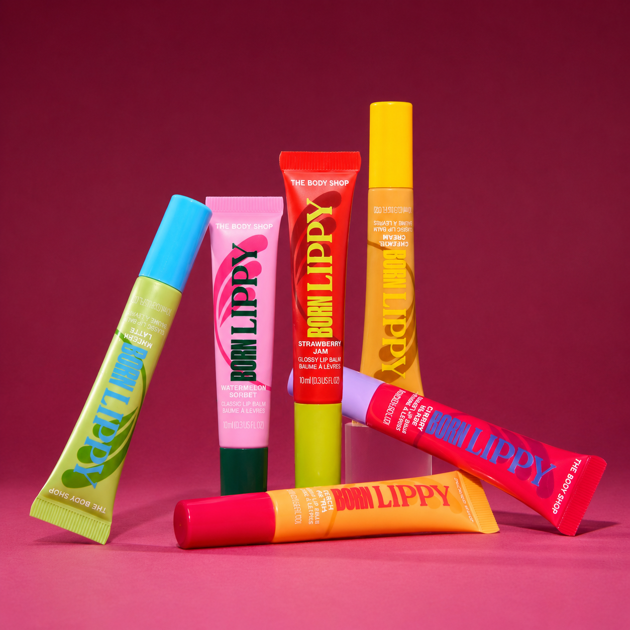 Collection of colorful lip balm tubes on a pink background