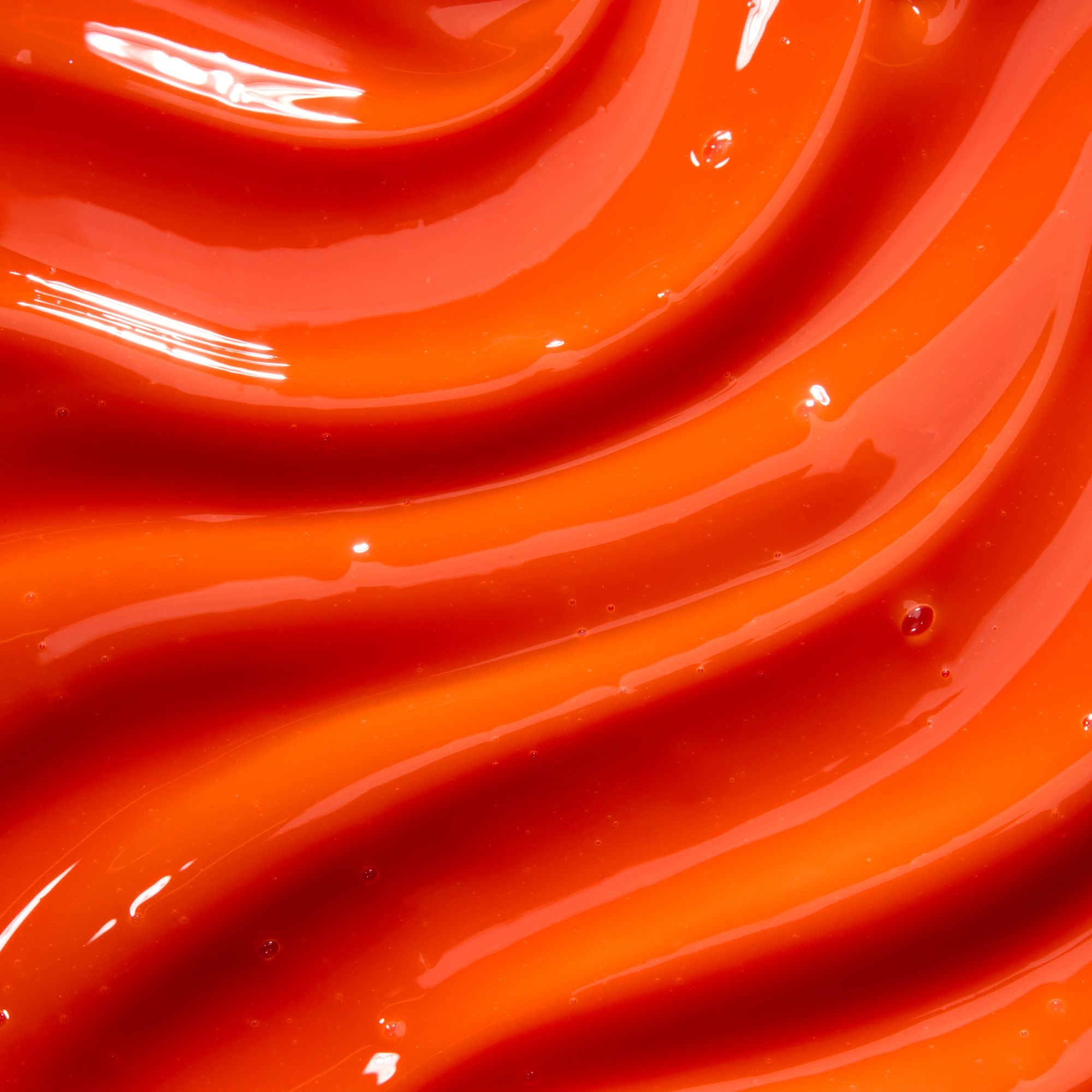 Close-up of smooth, orange- red coloured glossy lip gloss
