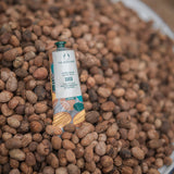 Shea butter tube on a bed of shea nuts with 'The Body Shop' branding.