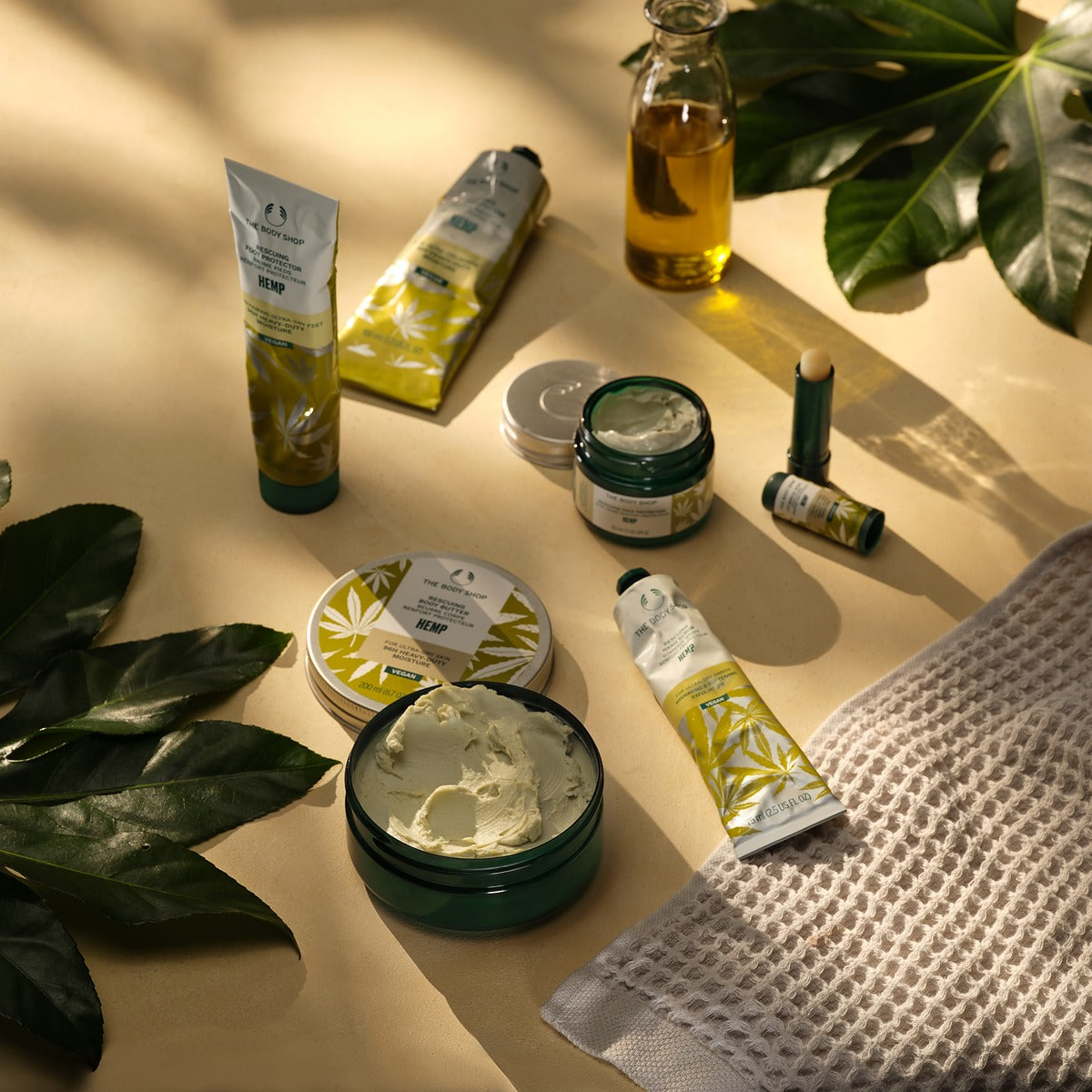 Collection of skincare products on a beige surface with green leaves.